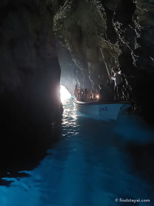 Dentro la Grotta Azzurra: piccole barche entrano da un ingresso basso.