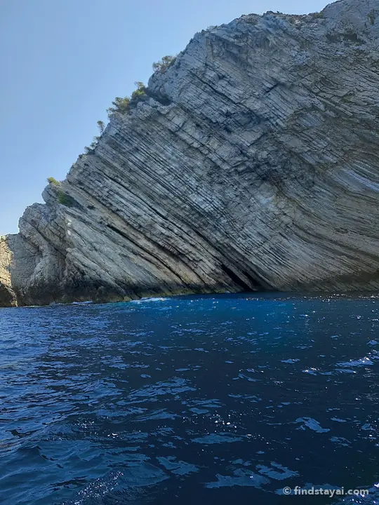 Strati di roccia inclinati che scendono nel blu profondo.
