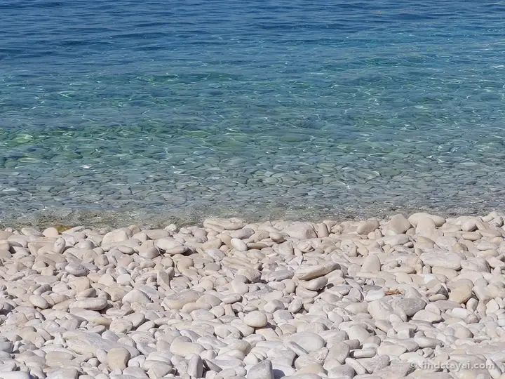 Acqua cristallina su ciottoli bianchi.
