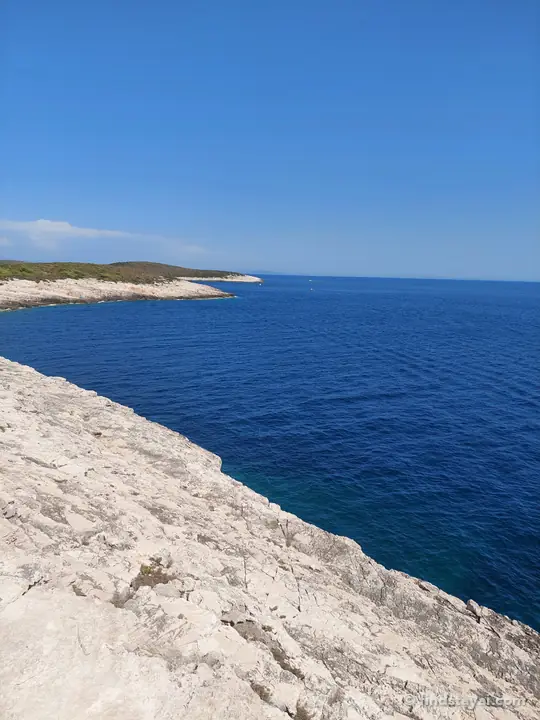 Costa rocciosa bianca e mare aperto sul lato selvaggio di Lissa.