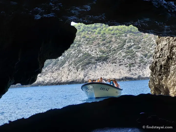 Vista da una grotta marina mentre arriva una barca da Comisa.